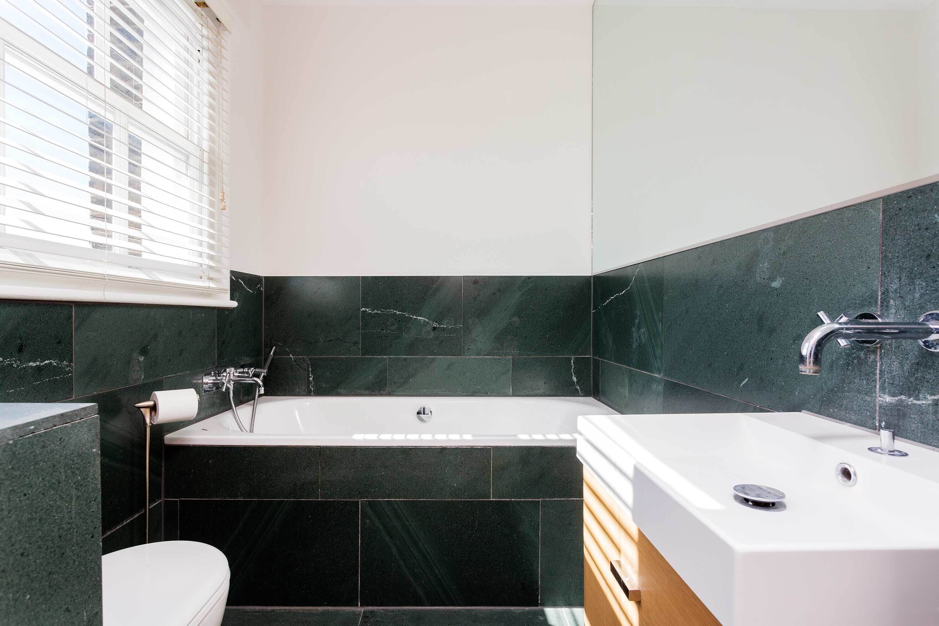 Een moderne badkamer met een bad, een douche en een wastafel.
