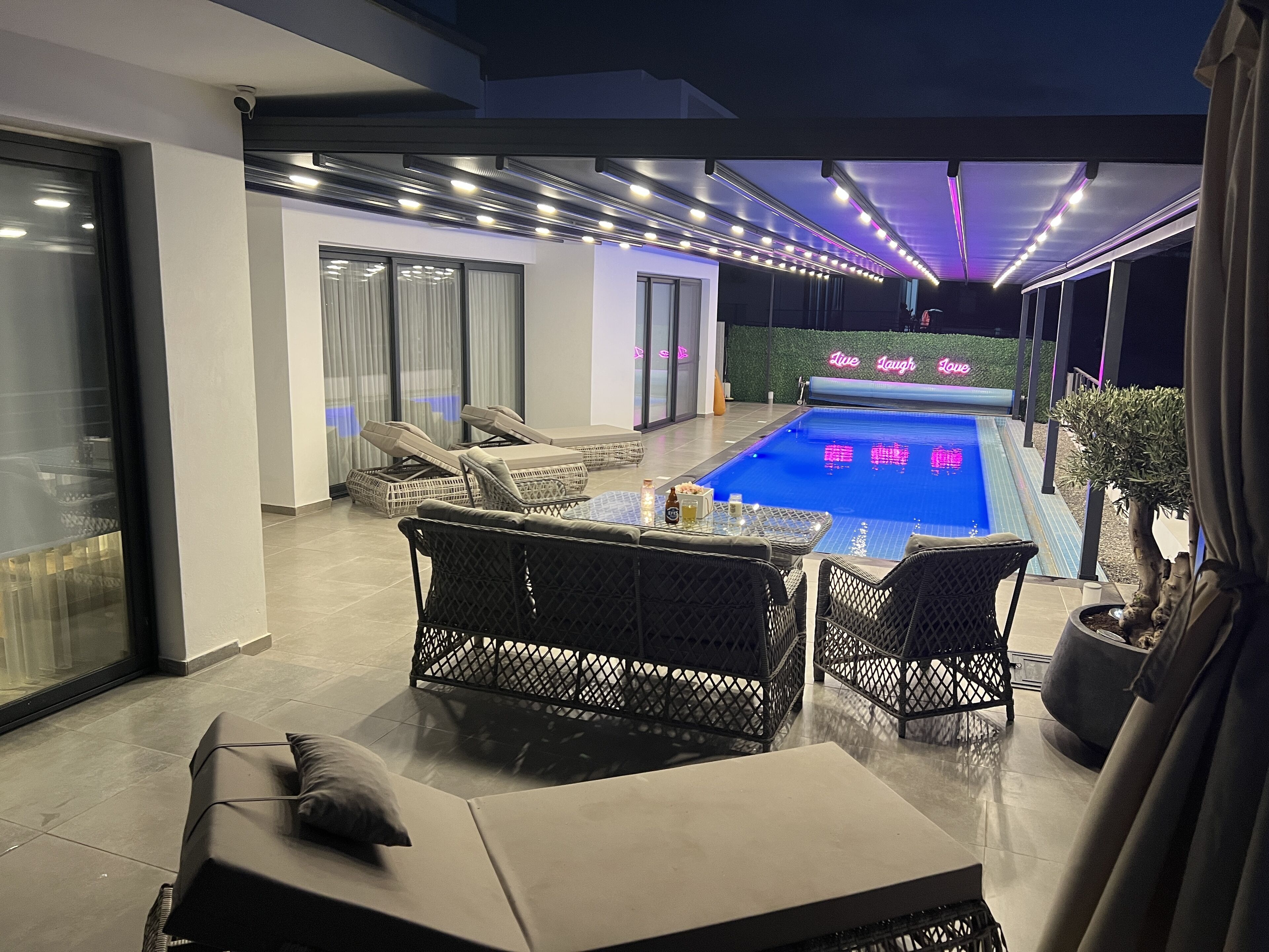 Night time by the pool with the roof closed and all the lights on