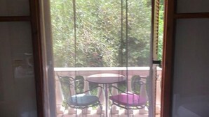Una stanza con un letto, una finestra con tende e un balcone con due sedie e un tavolo.