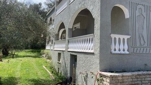 Un edificio con diversi balconi e finestre ad arco, immerso nel verde tra prati e alberi.