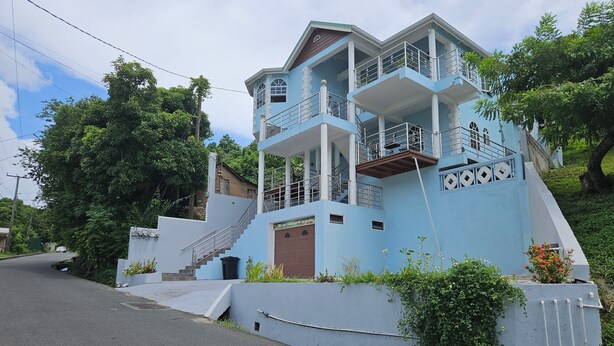Un immeuble à plusieurs étages, à la façade bleue, avec un escalier menant aux étages supérieurs et une porte de garage.