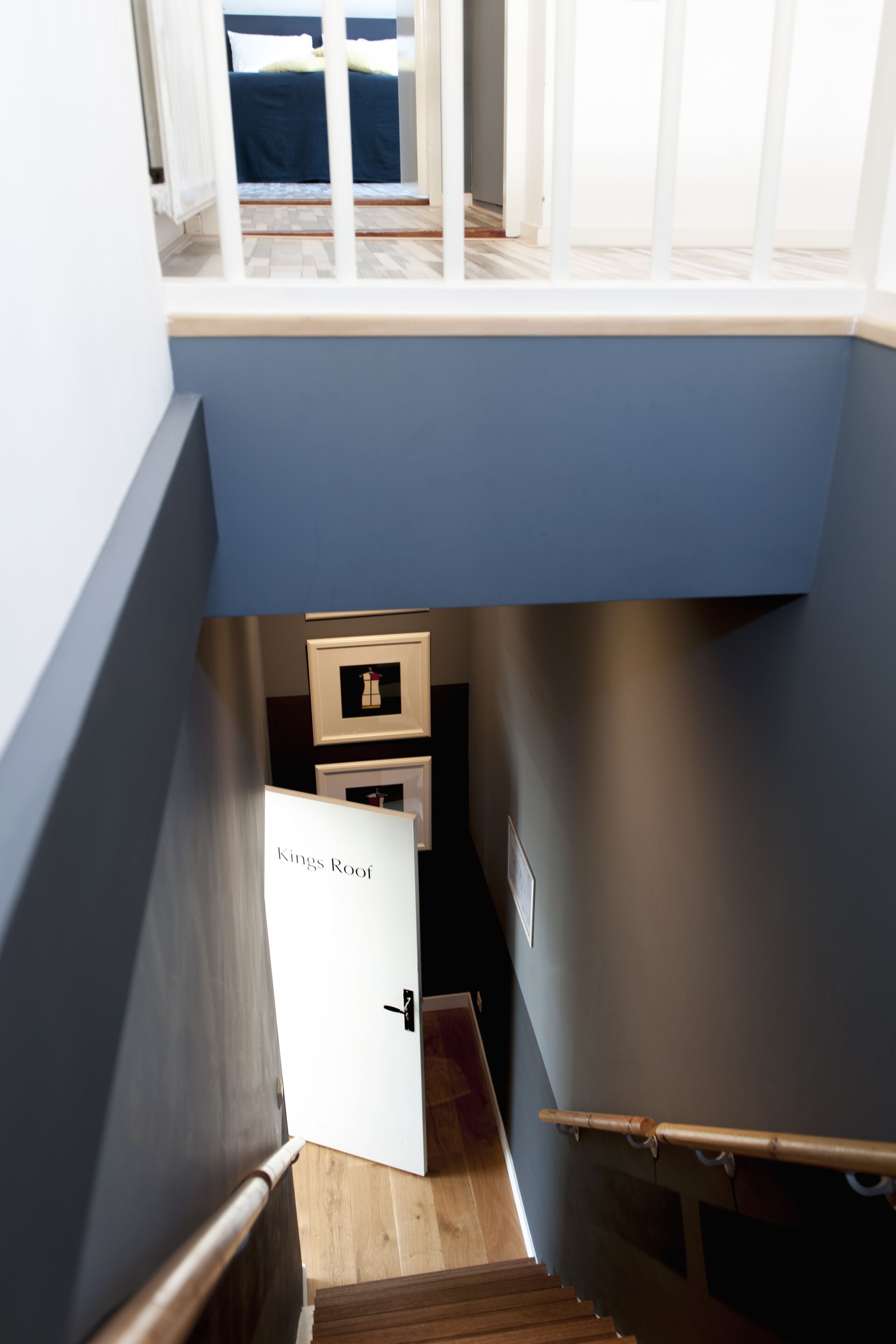 Eine enge Treppe führt zu einem Schlafzimmer mit Fenster, einer Tür mit der Aufschrift "Kings Roof" und einem Holzboden.