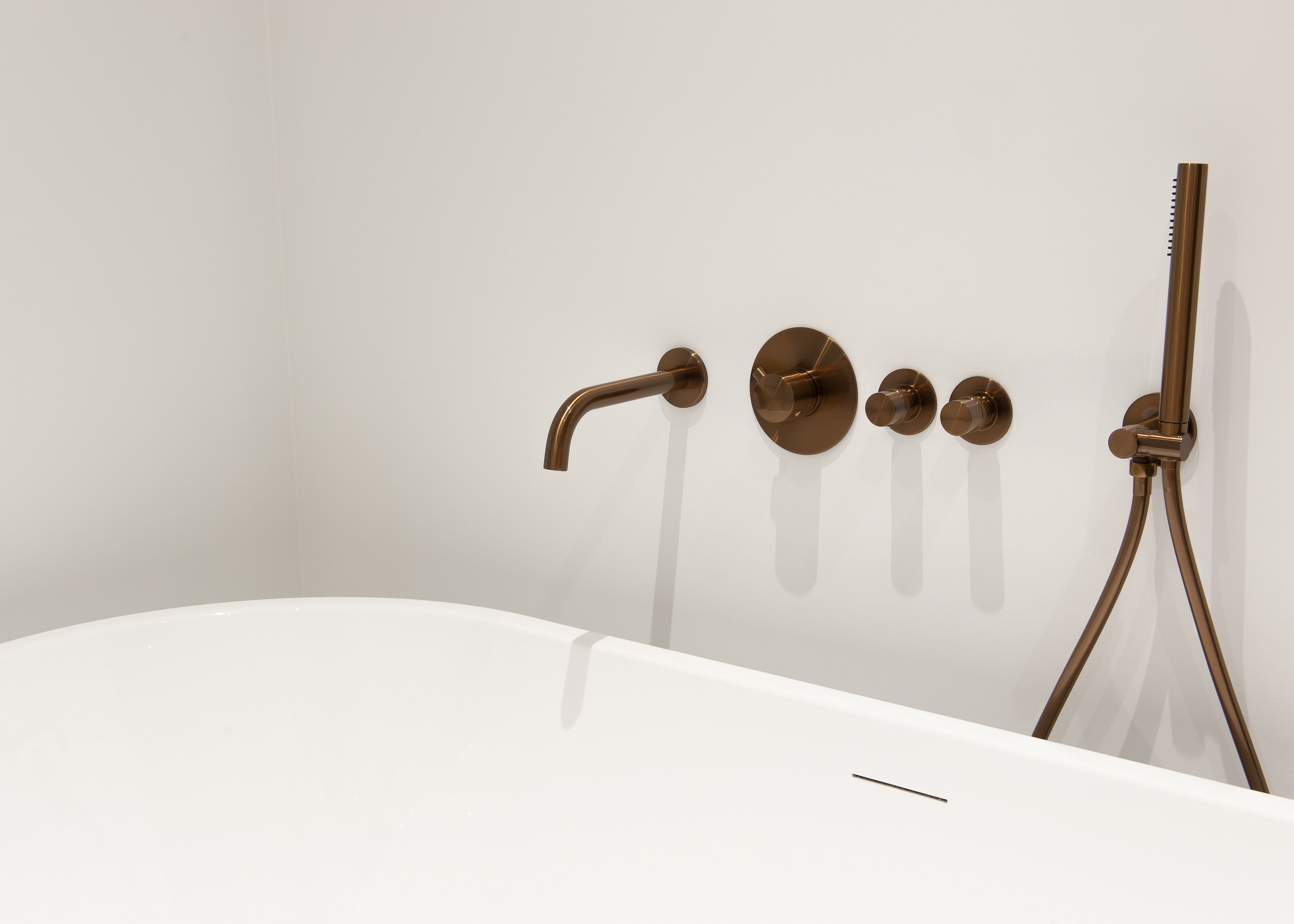 A modern bathroom with a white bathtub, a single showerhead, and a handheld shower attachment.