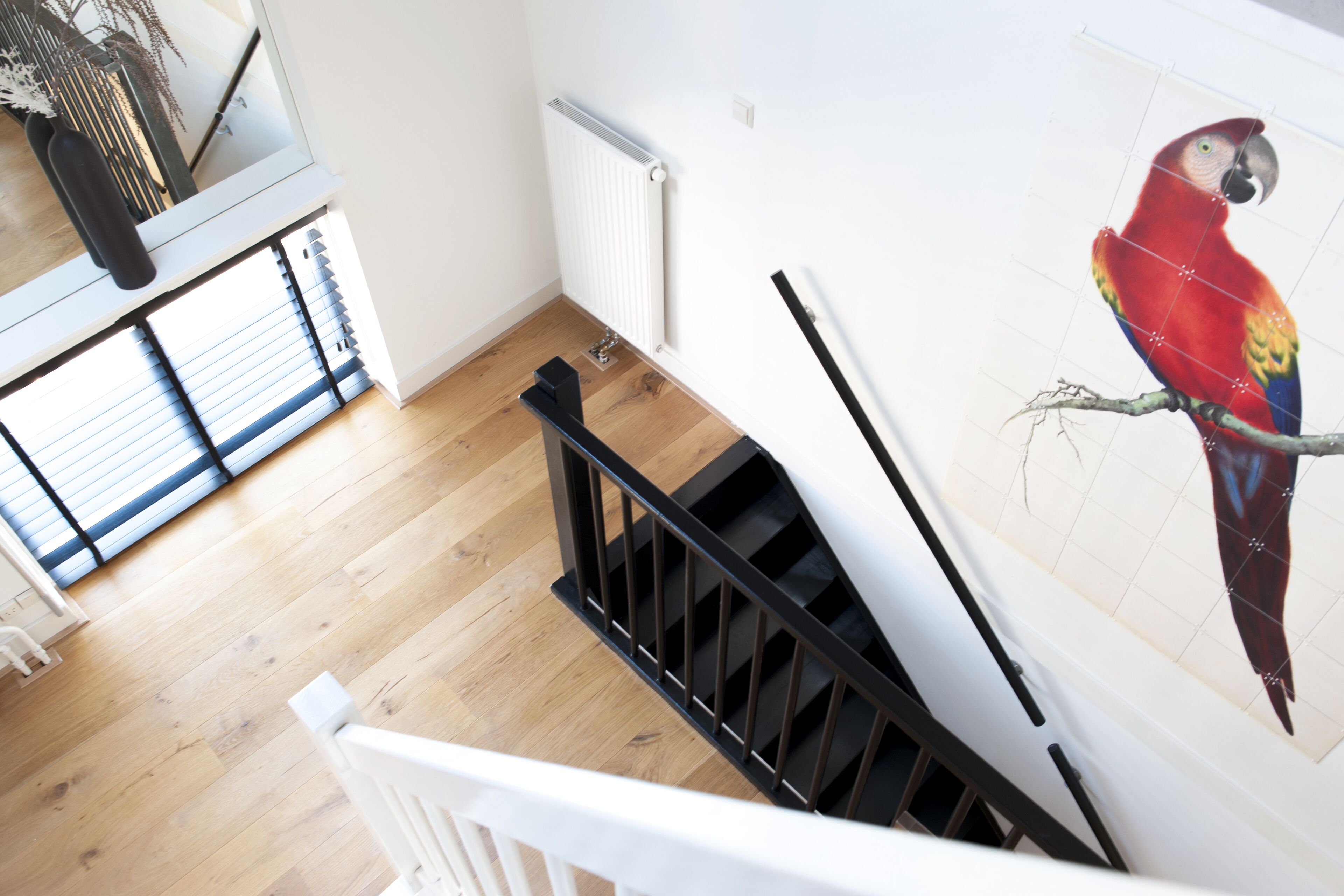 A staircase with a black handrail leading to a landing. A white radiator is mounted on the wall beside the staircase.