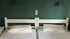 Ein Zimmer mit zwei Einzelbetten, einer grünen Wand und einer kleinen Uhr.