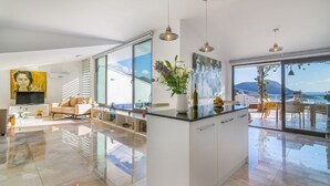 Una cocina moderna con una isla central, ventanas amplias y vistas al mar.