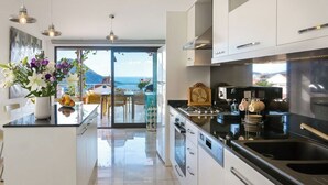 Una cocina moderna con una isla central, electrodomésticos de acero inoxidable y vistas al mar.