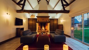 A cozy living room with a fireplace, two sofas, a TV, and a large window with a view of the outdoors. - Clos Céleste - Campagne d'Etretat (Ecrainville)