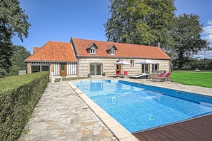 Una casa con piscina, sendero de piedra y zona de estar al aire libre.