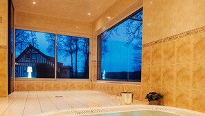 A spa area with a hot tub, large windows, and a view of a house. - Clos Céleste - Campagne d'Etretat (Ecrainville)