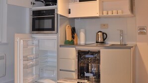 A compact kitchen with a built-in oven, a dishwasher, and a microwave. - LARPOTE LODGE - LUTON (LUTON)