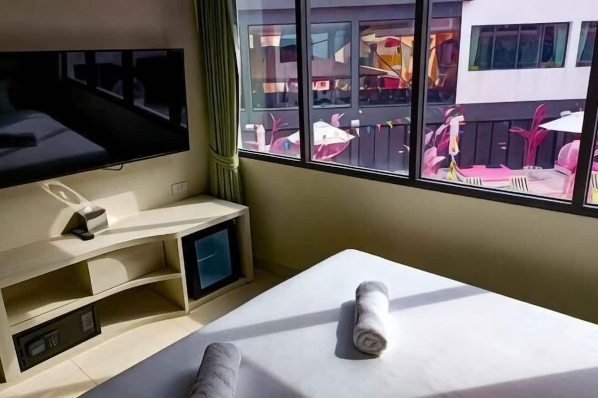 Quarto de hotel com televisão, mesa de massagem e vista para a área externa.
