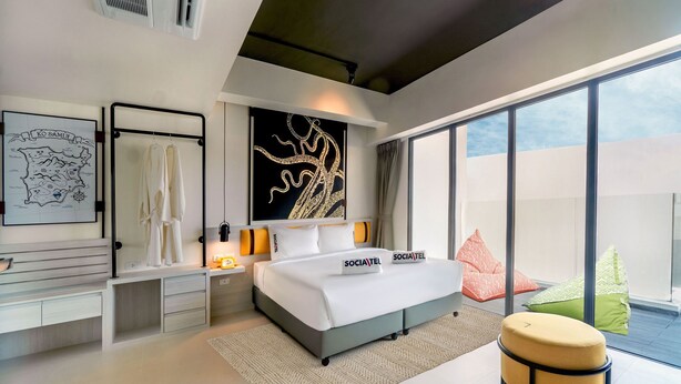 Une chambre à coucher moderne, dotée d’un grand lit, d’un bureau et offrant une vue sur le ciel grâce à de grandes fenêtres.