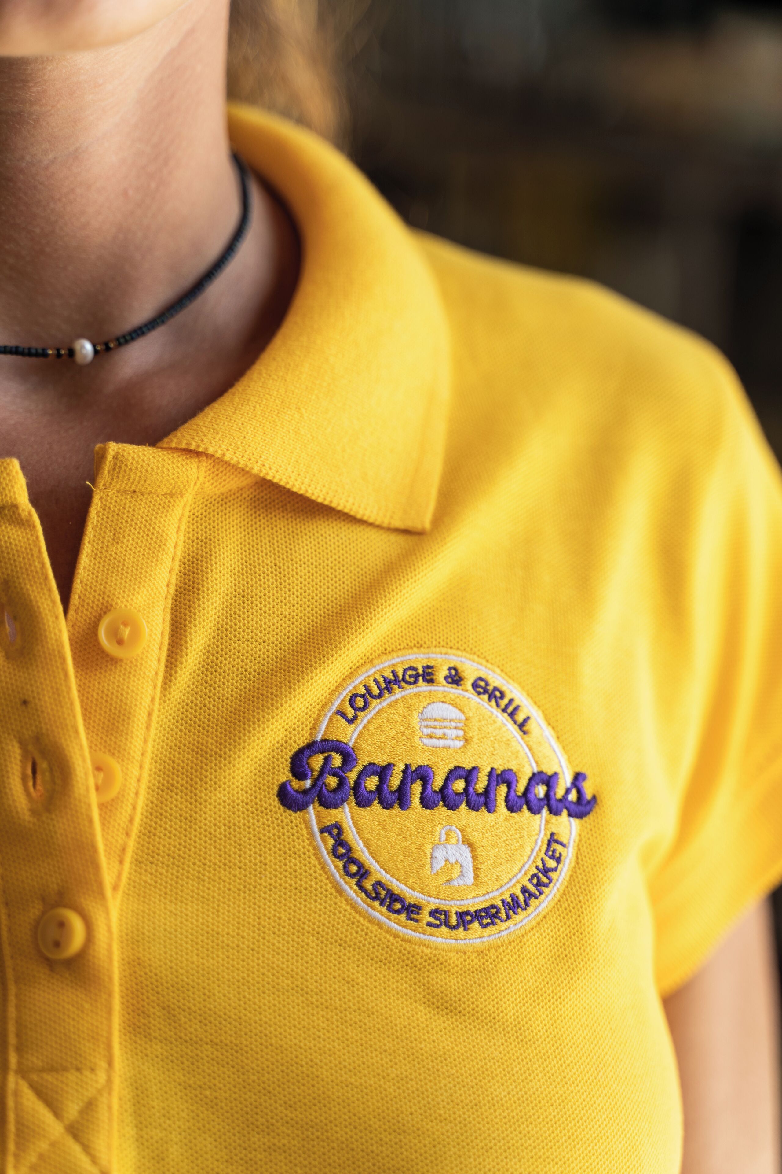 Una camisa polo amarilla con un logotipo que dice "Bananas" y "Polsde Supermarket".