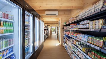 Un pasillo de supermercado con bebidas refrigeradas y estantes llenos de diversos productos alimenticios.