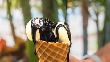 A hand holding a waffle cone with chocolate and banana toppings.