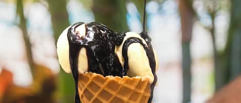 A hand holding a waffle cone with chocolate and banana toppings.