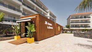 Een modern gebouw met een houten gevel en een bord met de tekst 'Hotel in the Sun'.