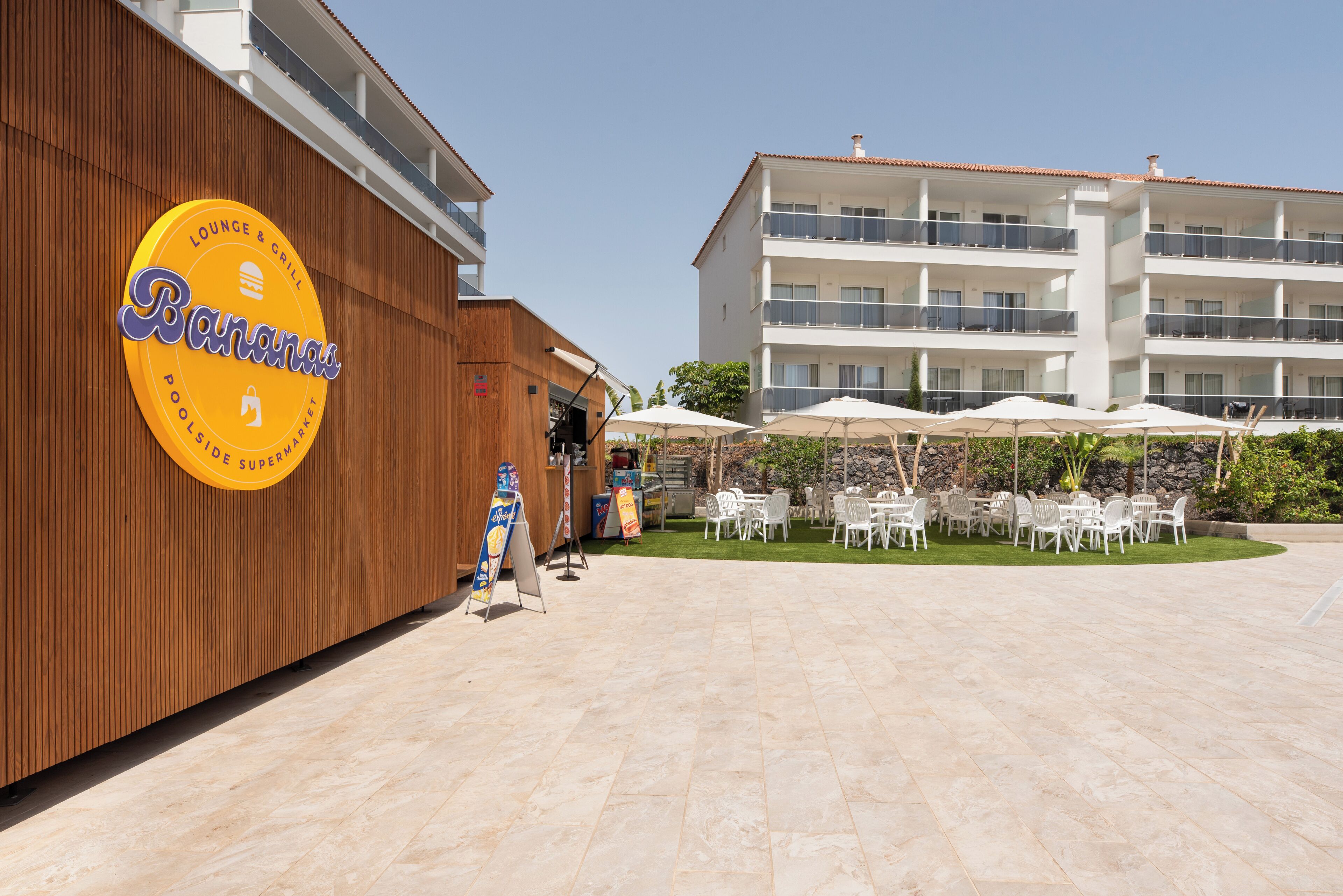 Ein Hotel mit Poolbereich, Außenbereich zum Sitzen und einer Beschilderung für Lounge und Grill.