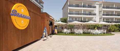 Un hotel con zona de piscina, asientos al aire libre y un letrero para un bar y parrilla.