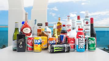A variety of beverages including wine, spirits, and energy drinks on a table with a view of the sea.