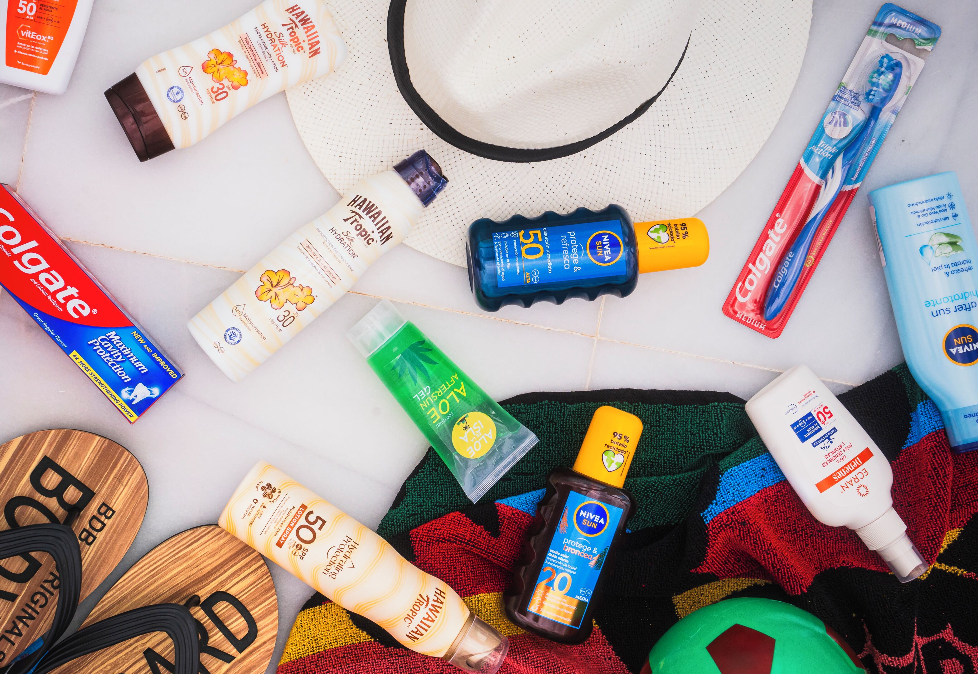A variety of personal care products and a hat on a white surface.