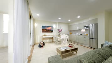 A modern living room with a sofa, coffee table, and a dining area with a table and chairs.
