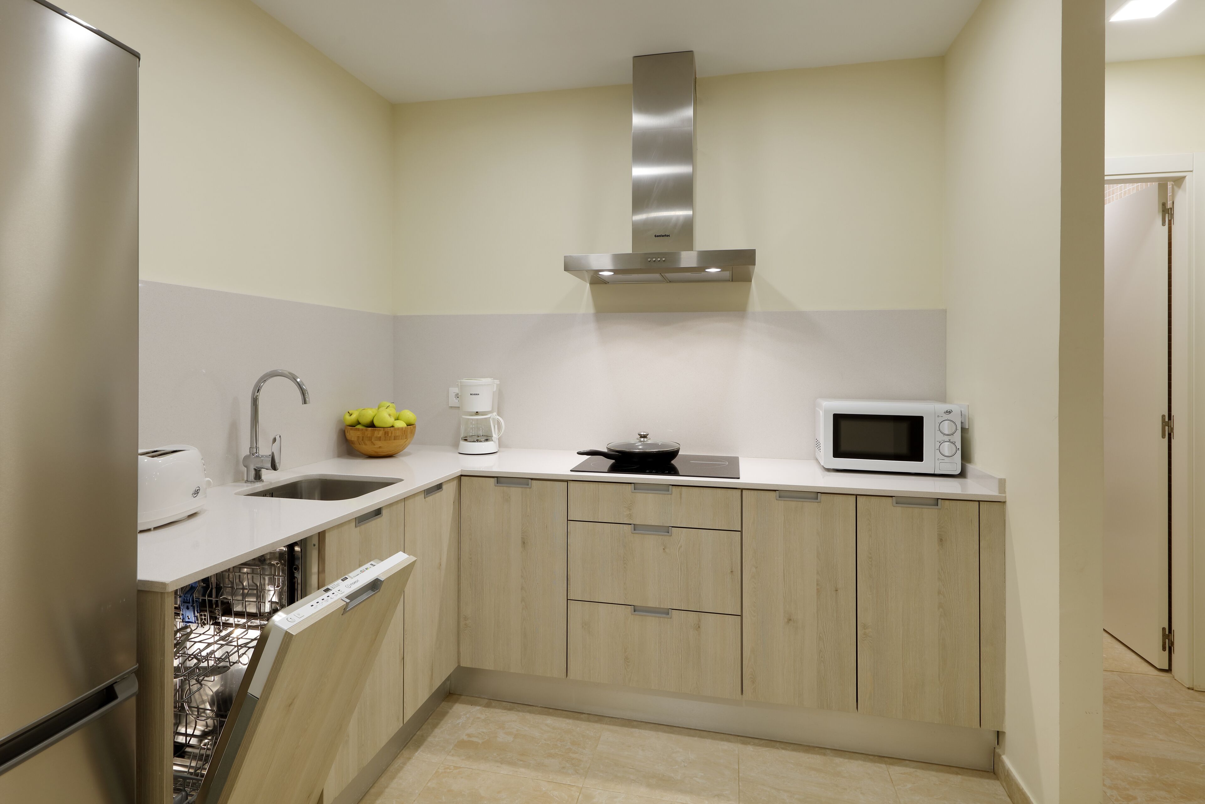 A compact kitchen with a dishwasher, a microwave, a toaster, and a coffee maker.