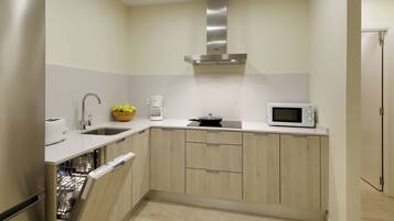 A compact kitchen with a dishwasher, a microwave, a toaster, and a coffee maker.