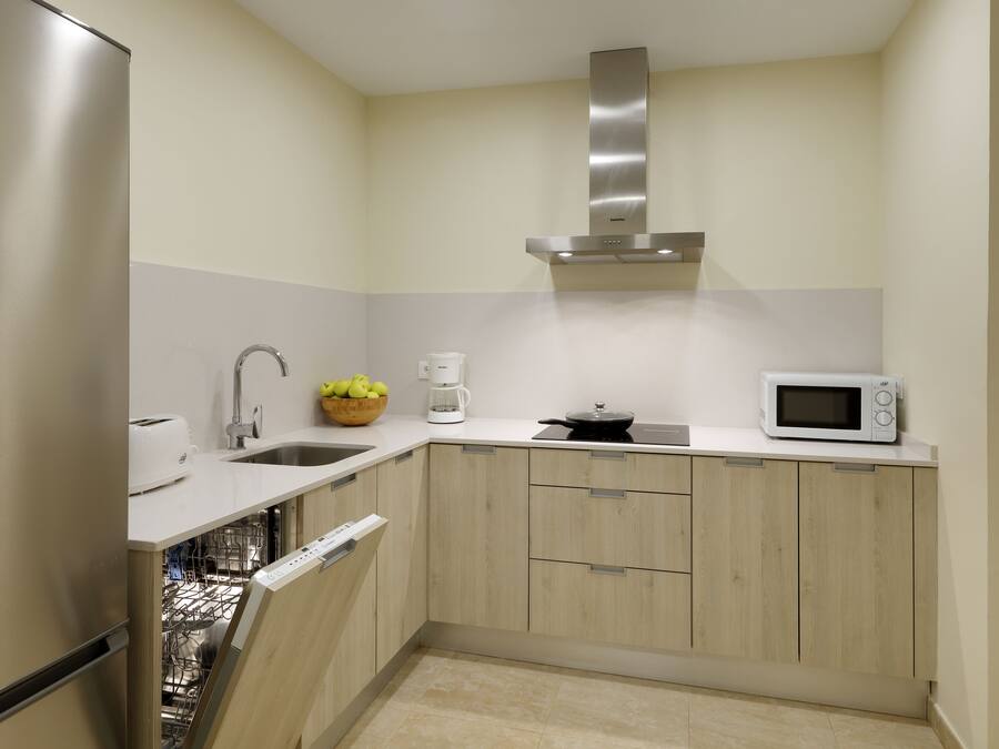 A compact kitchen with a dishwasher, a microwave, a toaster, and a coffee maker.