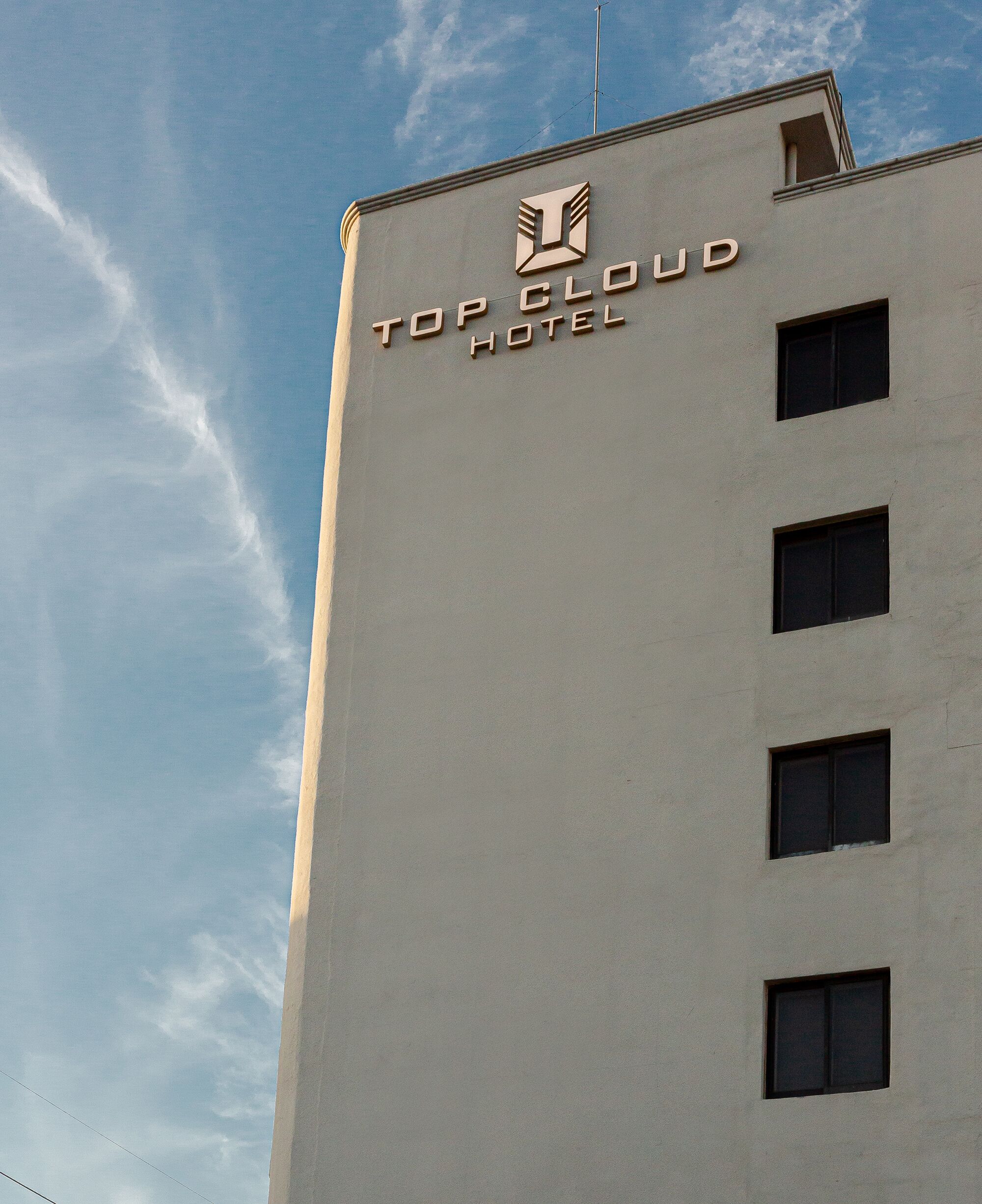A tall building with the sign "Top Cloud Hotel" and a logo above the text.