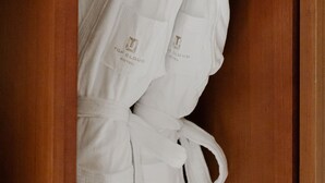 A wooden wardrobe with two white robes hanging inside. - Topcloud Hotel Iksan (Iksan)