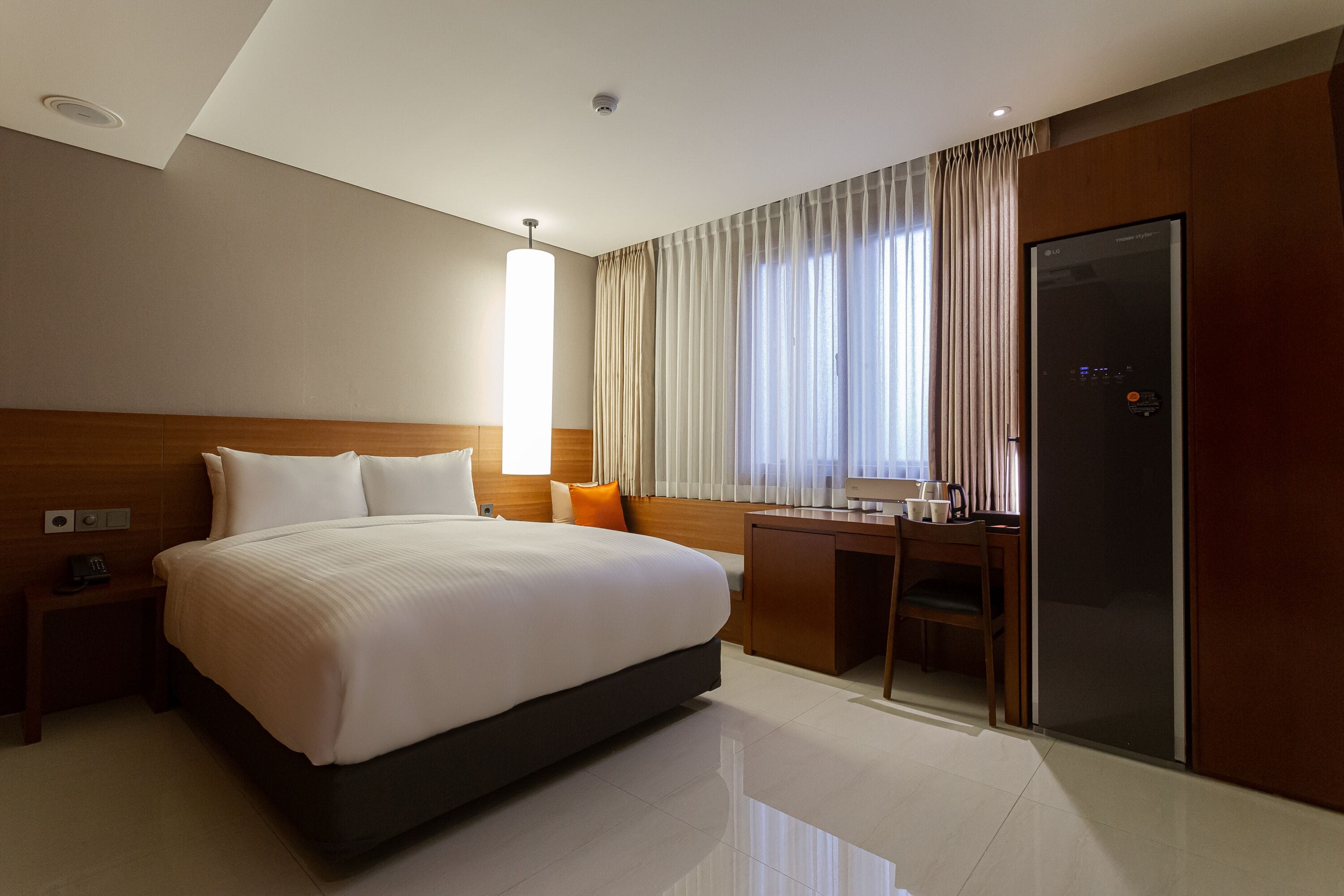 A hotel room with a large bed, a desk, and a wardrobe.