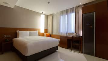 Een hotelkamer met een groot bed, een bureau en een kledingkast.