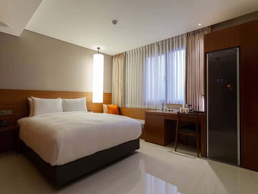 Una habitación de hotel con una cama grande, un escritorio y un armario.