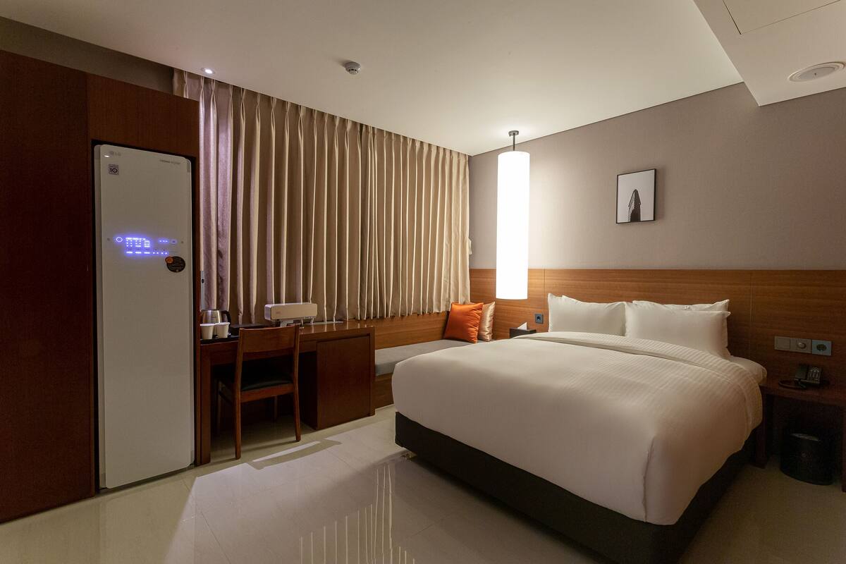 Ein Hotelzimmer mit Bett, Schreibtisch, Stuhl, Lampe und einem Bild an der Wand.