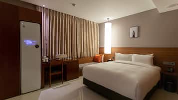 A hotel room with a bed, a desk, a chair, a lamp, and a picture on the wall.