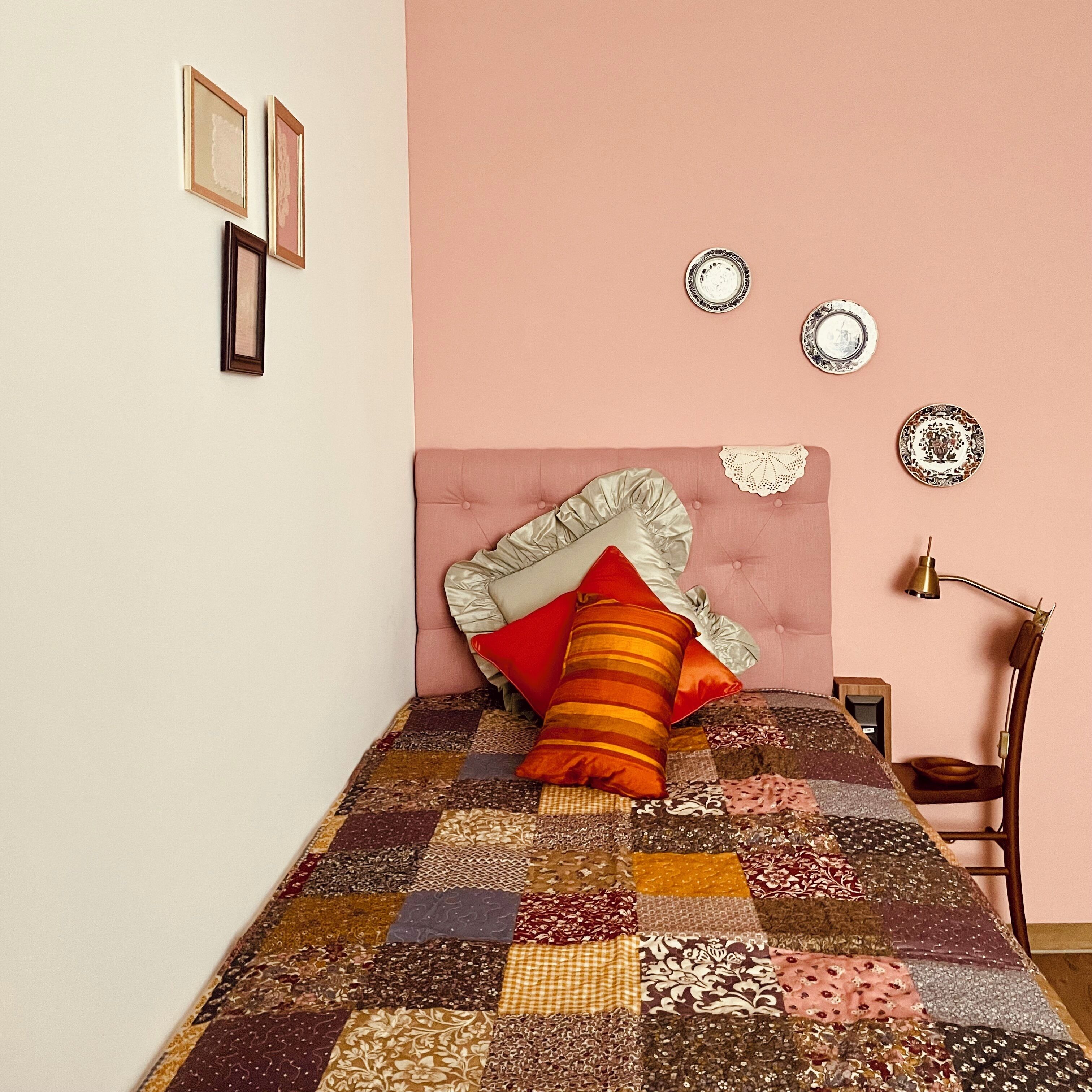 Een slaapkamer met een bed, een stoel en decoratieve wandversiering.