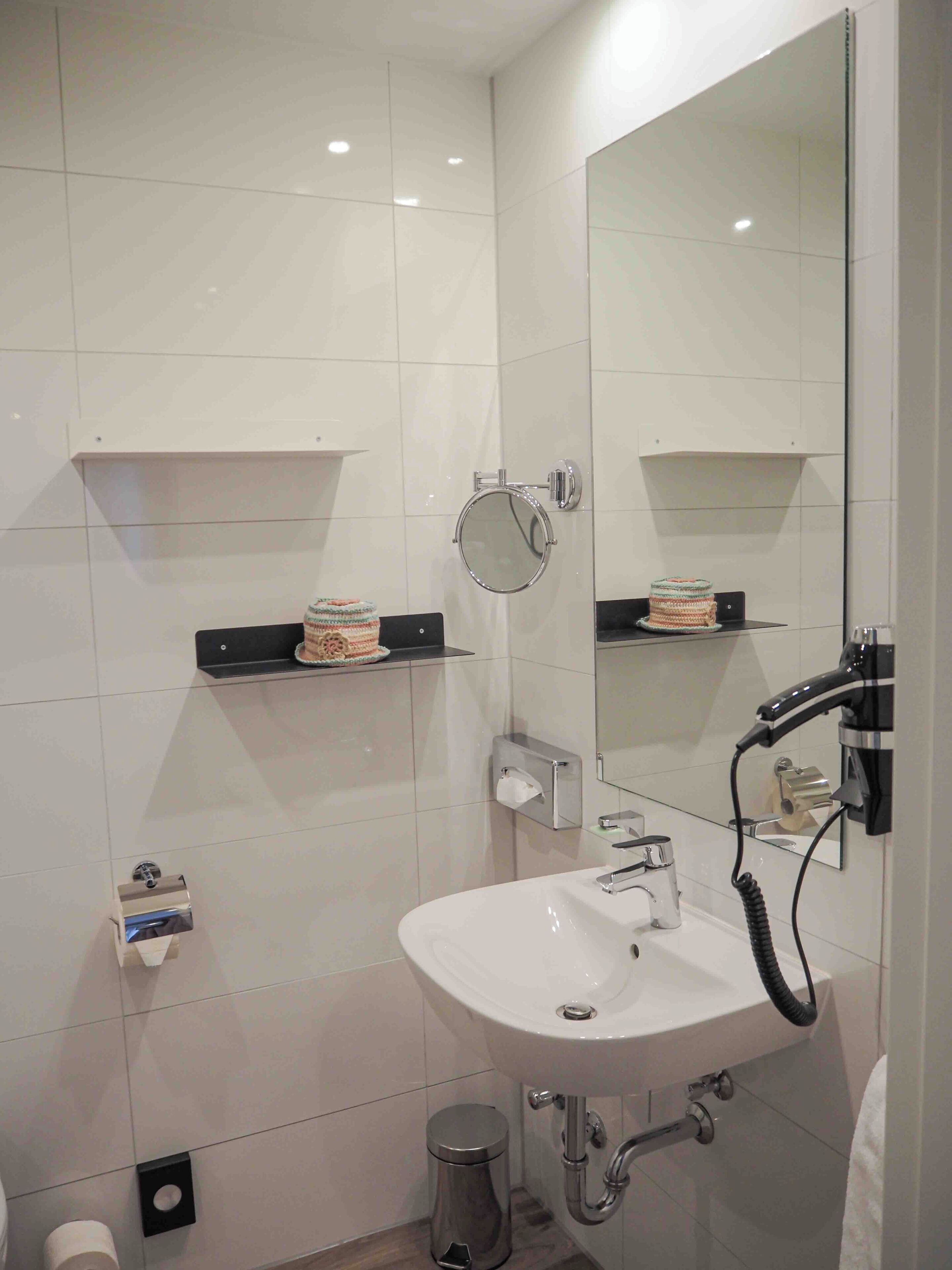 A modern bathroom with a white sink, mirror, and chrome fixtures.