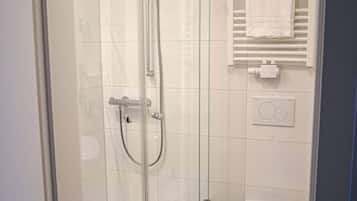 A modern bathroom with a glass-enclosed shower, a white toilet, and a towel rack.