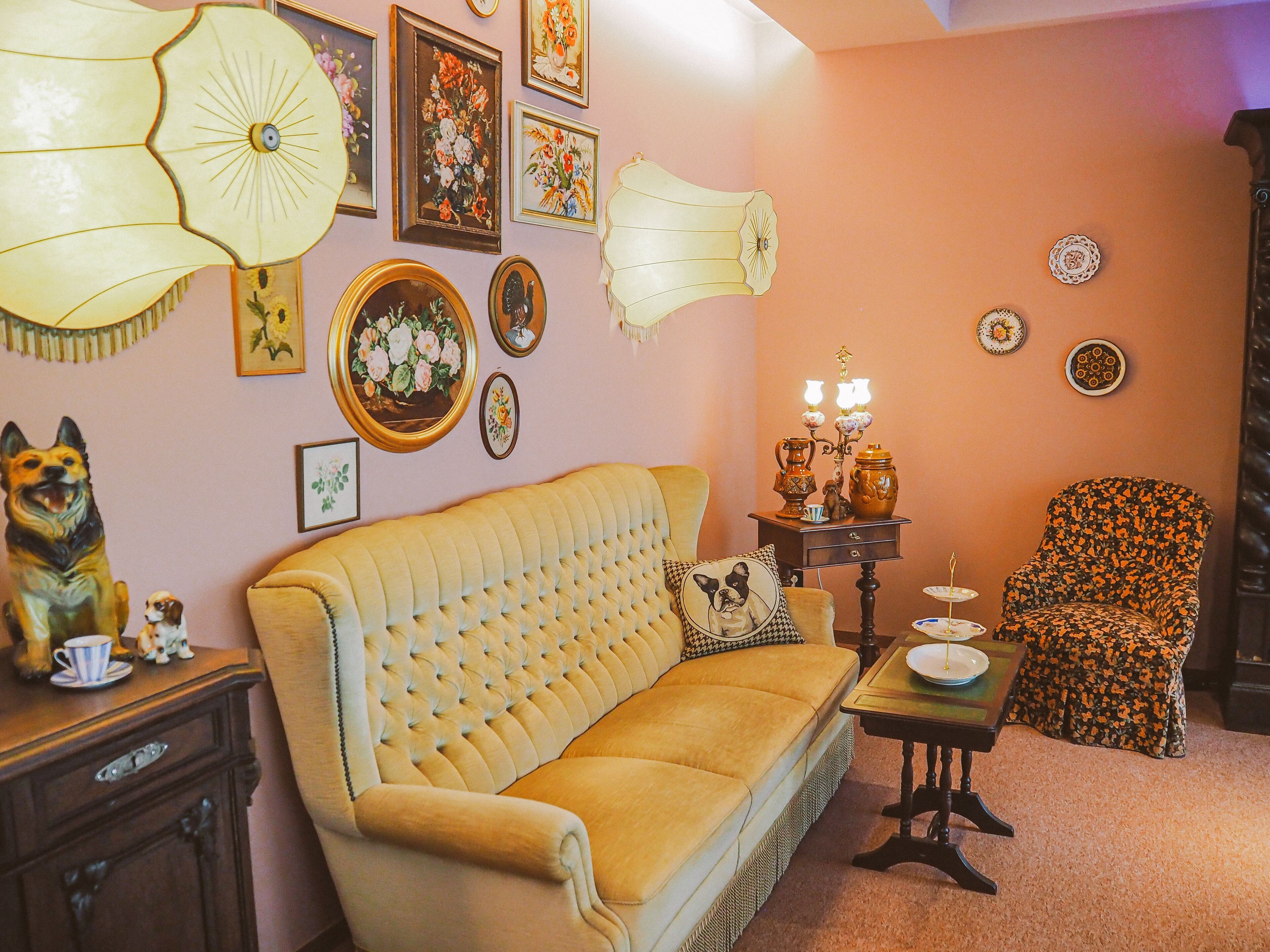 Una sala de estar acogedora con un sofá amarillo, un sillón estampado y una mesita con una lámpara.