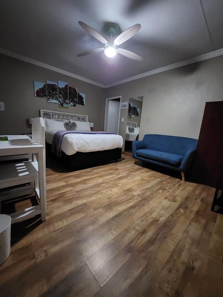 Une chambre à coucher avec un lit, un bureau, un canapé bleu et un ventilateur de plafond.