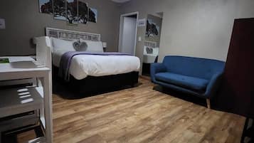 Une chambre à coucher avec un lit, un bureau, un canapé bleu et un ventilateur de plafond.