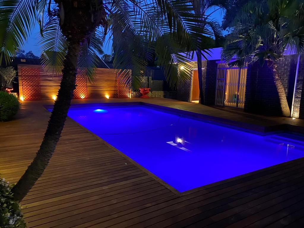 Ein Schwimmbad mit Holzterrasse und Palmen.