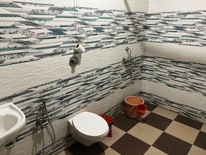 A bathroom with patterned tiles, a white sink, a toilet, and a shower.