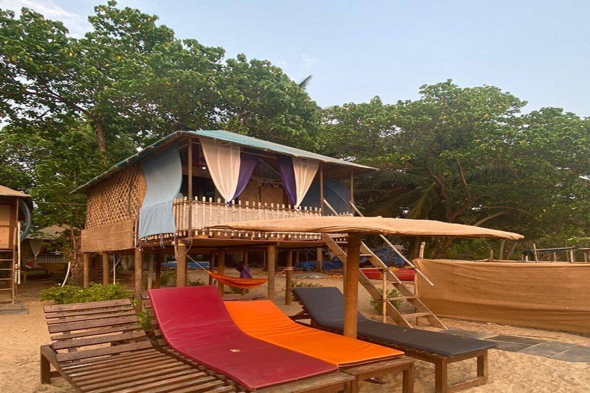 A beachside wooden structure with a covered seating area, a slide, and a hammock.