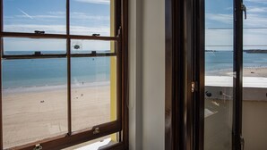 Une vue depuis une fenêtre donnant sur une plage, avec un ciel dégagé.