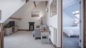 Une chambre confortable située sous les toits, avec un plafond en pente, une cheminée, un lit, une petite table et un téléviseur.