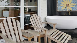 A wooden deck with Adirondack chairs, a white bathtub, and a mosaic wall art piece. - Romantic Ocean View Studio @ Stanwell Tops (Stanwell Tops)
