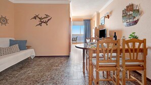 A room with a dining table, chairs, a sofa, and a ship decoration on the wall. - Vacation Home 'Marazul' with Sea View, Balcony & Wi-Fi (Tacoronte)